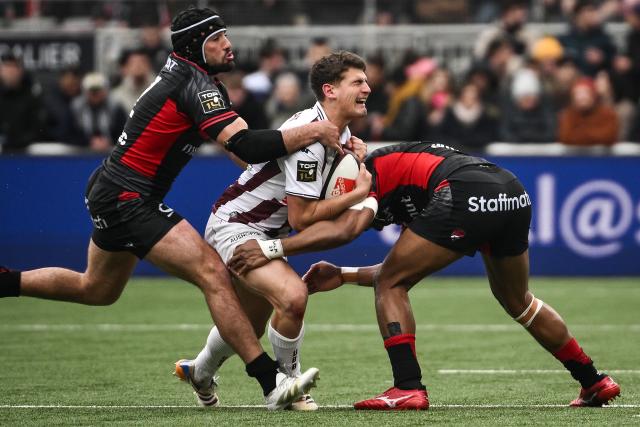 Bordeaux-Begles' Irish fly-half Joseph Laharrague (C) is tackled by Lyon's Fijian centre Iosefo Masi (R) as he runs with the ball during the French Top14 rugby union match between Lyon Olympique Universitaire Rugby and Union Bordeaux-Begles (UBB) at the Gerland Stadium in Lyon, central-eastern France on March 28, 2026. (Photo by ARNAUD FINISTRE / AFP)