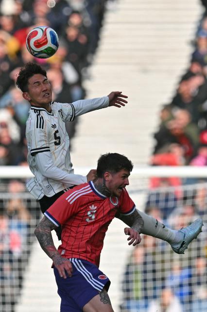Japan's defender Tsuyoshi Watanabe wins a header under pressure from Scotland's striker #09 Lyndon Dykes during the friendly International football match between Scotland and Japan at Hampden Park, in Glasgow, on March 28, 2026. (Photo by ANDY BUCHANAN / AFP)