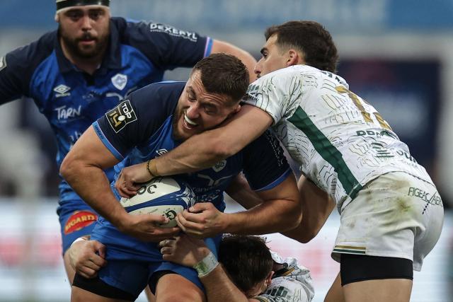 Castres' French hooker Teddy Durand (C) is tackled by Montauban's French centre Simon Renda (R) during the French Top 14 rugby union match between Castres Olympique and US Montauban at Stade Pierre Fabre in Castres, southern France on March 28, 2026. (Photo by Valentine CHAPUIS / AFP)