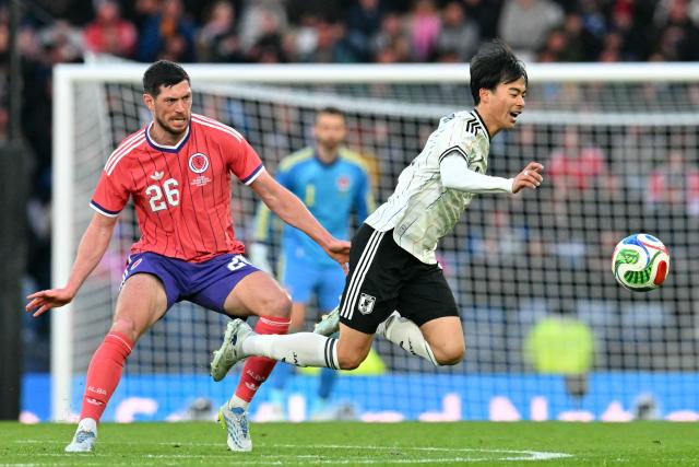 Japan's midfielder Kaoru Mitoma (R) is tripped by Scotland's defender #16 Scott McKenna (L) during the friendly International football match between Scotland and Japan at Hampden Park, in Glasgow, on March 28, 2026. (Photo by ANDY BUCHANAN / AFP)