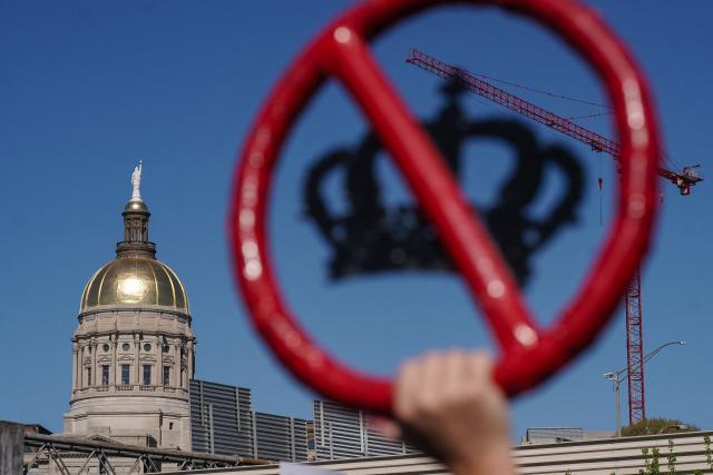 A person holds up a crown with a red line through it near the Georgia state Capitol building during the "No Kings" national day of protest in Atlanta, Georgia, on March 28, 2026. Nationwide protests against US President Donald Trump are expected Saturday as millions of people vent fury over what they see as his authoritarian bent and other forms of cruel, law-trampling governance. It is the third time in less than a year that Americans will take to the streets as part of a grassroots movement called "No Kings," the most vocal and visual conduit for opposition to Trump since he began his second term in January 2025. (Photo by Elijah Nouvelage / AFP)
