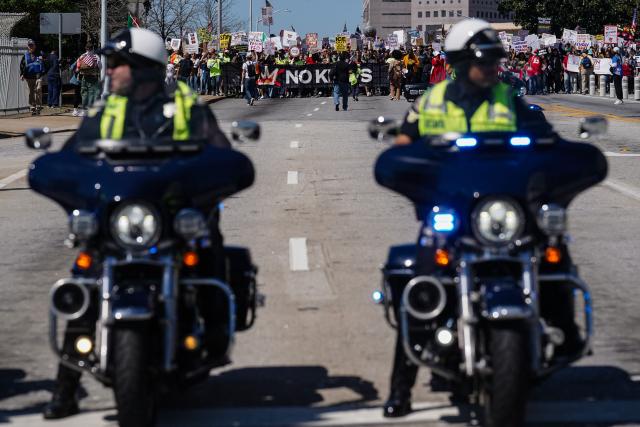 Police on motorbikes wait ahead of people marching near the Georgia state Capitol building during the "No Kings" national day of protest in Atlanta, Georgia, on March 28, 2026. Nationwide protests against US President Donald Trump are expected Saturday as millions of people vent fury over what they see as his authoritarian bent and other forms of cruel, law-trampling governance. It is the third time in less than a year that Americans will take to the streets as part of a grassroots movement called "No Kings," the most vocal and visual conduit for opposition to Trump since he began his second term in January 2025. (Photo by Elijah Nouvelage / AFP)