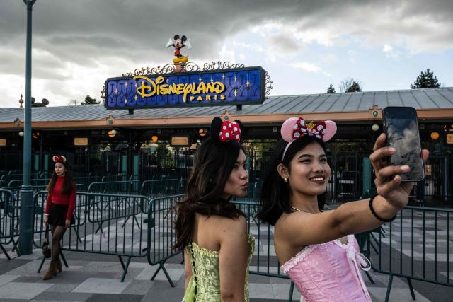 Visitors pose for a selfie at the entrance of Disneyland Paris in Marne-la-Vallee, east of Paris on March 28, 2026. (Photo by Blanca CRUZ / AFP)