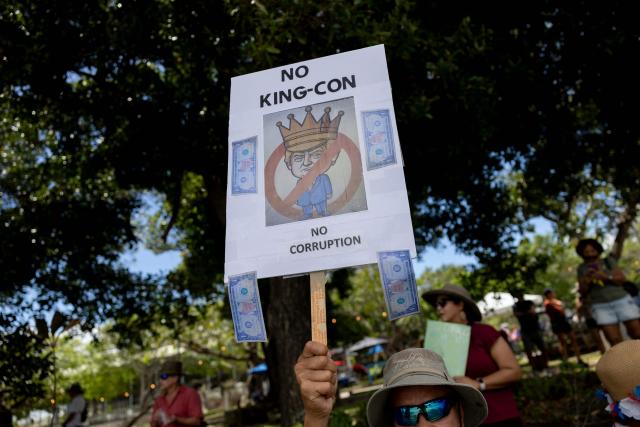 A demonstrator holds a sign featuring an image of US President Donald Trump in a crown during the "No Kings" national day of protest that included opposition to the proposed Esencia coastal development project in San Juan, Puerto Rico, on March 28, 2026. Nationwide protests against US President Donald Trump are expected Saturday as millions of people vent fury over what they see as his authoritarian bent and other forms of cruel, law-trampling governance. It is the third time in less than a year that Americans will take to the streets as part of a grassroots movement called "No Kings," the most vocal and visual conduit for opposition to Trump since he began his second term in January 2025. (Photo by Ricardo ARDUENGO / AFP)