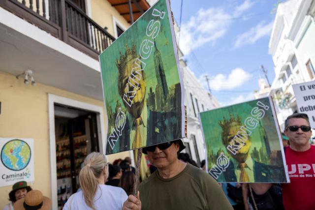 People hold signs featuring images of US Presdient Donald Trump in a crown during the "No Kings" national day of protest that included opposition to the proposed Esencia coastal development project in San Juan, Puerto Rico, on March 28, 2026. Nationwide protests against US President Donald Trump are expected Saturday as millions of people vent fury over what they see as his authoritarian bent and other forms of cruel, law-trampling governance. It is the third time in less than a year that Americans will take to the streets as part of a grassroots movement called "No Kings," the most vocal and visual conduit for opposition to Trump since he began his second term in January 2025. (Photo by Ricardo ARDUENGO / AFP)