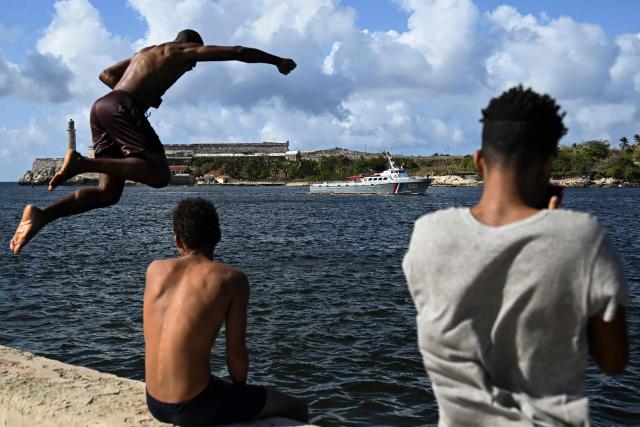 A man jumps into the sea as a Cuban Border Guard vessel that took part in the search for the sailboats bringing humanitarian aid to Cuba arrives at the port of Havana on March 28, 2026. Two sailboats carrying humanitarian aid to crisis-hit Cuba reached Havana on Saturday after a long journey from Mexico during which they went missing and triggered a search-and-rescue mission, (Photo by Yamil LAGE / AFP)