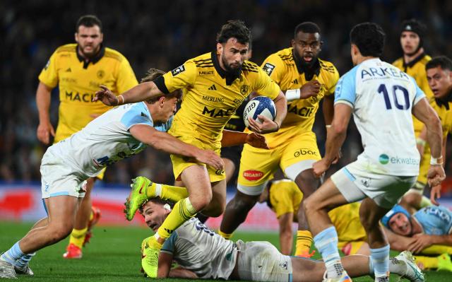 La Rochelle's French fly-half Antoine Hastoy (C) is tackled as he runs with the ball during the French Top14 rugby union match between Aviron Bayonnais (Bayonne) and Stade Rochelais (La Rochelle) at the Stade Jean Dauger in Bayonne, south-western France, on March 28, 2026. (Photo by Gaizka IROZ / AFP)