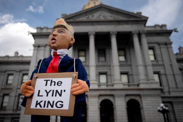 A puppet in the likeness of US President Donald Trump holding a sign reading "The Lying King" is held up held up in front of the Colorado State Capital during the "No Kings" national rally in Denver, Colorado, on March 28, 2026. Nationwide protests against US President Donald Trump are expected Saturday as millions of people vent fury over what they see as his authoritarian bent and other forms of cruel, law-trampling governance. It is the third time in less than a year that Americans will take to the streets as part of a grassroots movement called "No Kings," the most vocal and visual conduit for opposition to Trump since he began his second term in January 2025. (Photo by Jason Connolly / AFP)