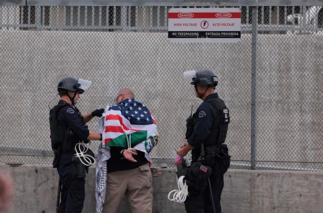 LAPD officers arrest a protestor following clashes near the Metropolitan Detention Center during the "No Kings" national day of protest in Los Angeles on March 28, 2026. Nationwide protests against US President Donald Trump are expected Saturday as millions of people vent fury over what they see as his authoritarian bent and other forms of cruel, law-trampling governance. It is the third time in less than a year that Americans will take to the streets as part of a grassroots movement called "No Kings," the most vocal and visual conduit for opposition to Trump since he began his second term in January 2025. (Photo by Etienne LAURENT / AFP)