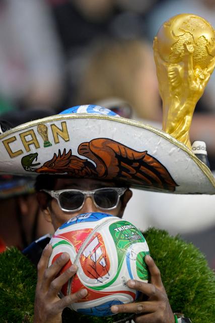 A Mexican fan wearing a hat and a figure of the World Cup kisses a Trionda ball during a friendly football match between Mexico and Portugal at the Banorte (formerly known as Azteca) Stadium in Mexico City on March 28, 2026. (Photo by Alfredo ESTRELLA / AFP)