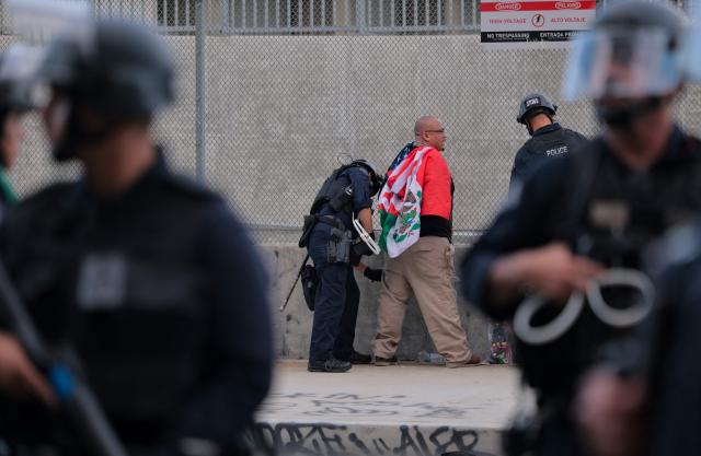 LAPD officers arrest a protestor following clashes near the Metropolitan Detention Center during the "No Kings" national day of protest in Los Angeles on March 28, 2026. Nationwide protests against US President Donald Trump are expected Saturday as millions of people vent fury over what they see as his authoritarian bent and other forms of cruel, law-trampling governance. It is the third time in less than a year that Americans will take to the streets as part of a grassroots movement called "No Kings," the most vocal and visual conduit for opposition to Trump since he began his second term in January 2025. (Photo by Etienne LAURENT / AFP)