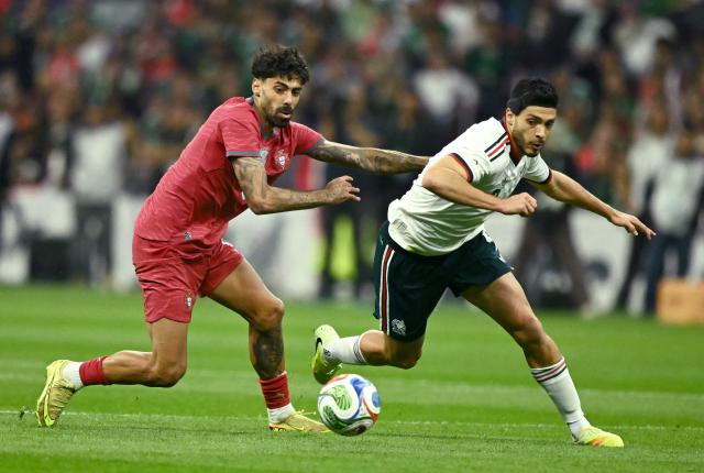 Portugal's defender #05 Samu Costa (L) and Mexico's forward #09 Raul Alonso Jimenez (R) fight for the ball during a friendly football match between Mexico and Portugal at the Banorte (formerly known as Azteca) Stadium in Mexico City on March 28, 2026. (Photo by CARL DE SOUZA / AFP)