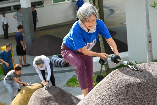 This photograph taken on March 17, 2026 shows Singaporean elders taking part in a parkour training session in Singapore. This is "geriatric parkour", where around 20 retirees learned to tackle a series of relatively demanding exercises, building their agility and enjoying a sense of camaraderie. (Photo by Roslan RAHMAN / AFP) / To go with "Singapore-Ageism" Focus by Martin ABBUGAO