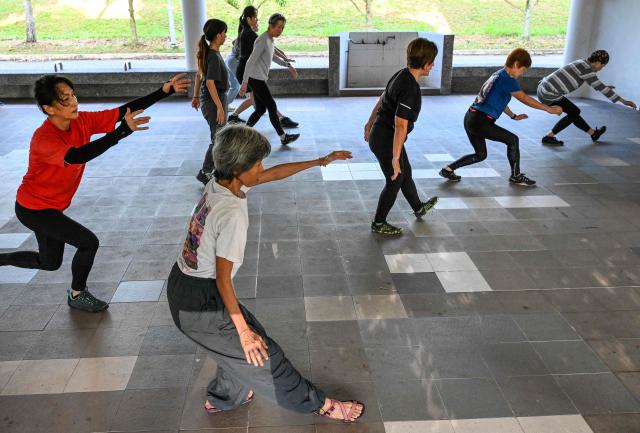 This photograph taken on March 17, 2026 shows Singaporean elders warming up before a parkour training session in Singapore. This is "geriatric parkour", where around 20 retirees learned to tackle a series of relatively demanding exercises, building their agility and enjoying a sense of camaraderie. (Photo by Roslan RAHMAN / AFP) / To go with "Singapore-Ageism" Focus by Martin ABBUGAO