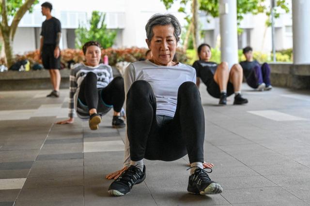 This photograph taken on March 17, 2026 shows Singaporean elders warming up before a parkour training session in Singapore. This is "geriatric parkour", where around 20 retirees learned to tackle a series of relatively demanding exercises, building their agility and enjoying a sense of camaraderie. (Photo by Roslan RAHMAN / AFP) / To go with "Singapore-Ageism" Focus by Martin ABBUGAO