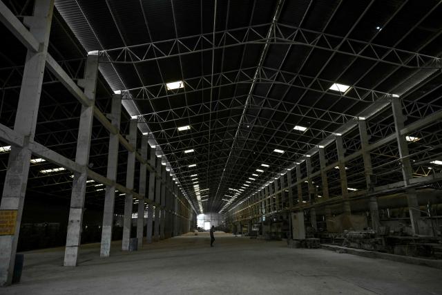 A worker walks across a ceramics tiles-manufacturing factory, that remains closed amid propane gas supply constraints and global energy crisis owing to the Middle East war, in Morbi on March 25, 2026. Blazing-hot kilns in India's $6.5 billion ceramics production hub employing hundreds of thousands of people have gone cold, shut down in an energy crunch sparked by the US-Israeli strikes on Iran. (Photo by Indranil MUKHERJEE / AFP)