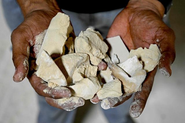 A worker shows clay used to make tiles at a ceramics factory, that remains closed amid propane gas supply constraints and global energy crisis owing to the Middle East war, in Morbi on March 25, 2026. Blazing-hot kilns in India's $6.5 billion ceramics production hub employing hundreds of thousands of people have gone cold, shut down in an energy crunch sparked by the US-Israeli strikes on Iran. (Photo by Indranil MUKHERJEE / AFP)