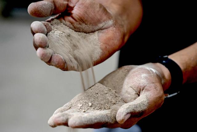 A worker shows clay granules used to make tiles at a ceramics factory, that remains closed amid propane gas supply constraints and global energy crisis owing to the Middle East war, in Morbi on March 25, 2026. Blazing-hot kilns in India's $6.5 billion ceramics production hub employing hundreds of thousands of people have gone cold, shut down in an energy crunch sparked by the US-Israeli strikes on Iran. (Photo by Indranil MUKHERJEE / AFP)