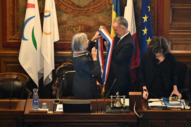 Paris' newly elected Mayor Emmanuel Grégoire receives his tricolour mayoral sash after being nominated during the inaugural city council session at the city hall of Paris on March 29, 2026. Emmanuel Grégoire, who was elected mayor of Paris by a wide margin over right wing candidate Rachida Dati, takes office on March 29, 2026 at the Paris City Hall to succeed Anne Hidalgo, who is stepping down after 12 years in office. (Photo by JULIEN DE ROSA / AFP)