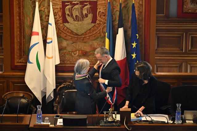 Paris' newly elected Mayor Emmanuel Grégoire receives his tricolour mayoral sash after being nominated during the inaugural city council session at the city hall of Paris on March 29, 2026. Emmanuel Grégoire, who was elected mayor of Paris by a wide margin over right wing candidate Rachida Dati, takes office on March 29, 2026 at the Paris City Hall to succeed Anne Hidalgo, who is stepping down after 12 years in office. (Photo by JULIEN DE ROSA / AFP)