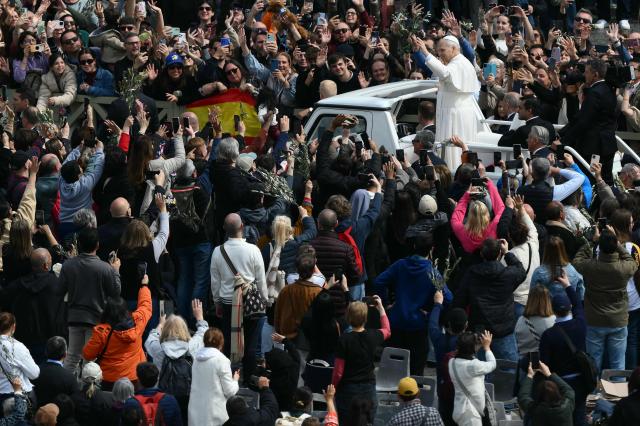 Pope Leo XIV greets the crowd as he leaves after the Palm Sunday mass at St Peter's square in the Vatican on March 29, 2026. (Photo by Marco BERTORELLO / AFP)