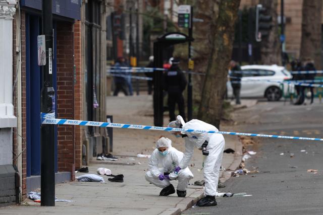 Police forensic officers work amongst a variety of personal items seen covering the road, inside a cordon set up on Friar Gate in central Derby, central England on March 29, 2026, following an incident the night before where a vehicle was driven into pedestrians. British police said they arrested a man after a car struck several pedestrians in a city in central England on Saturday night, leaving some victims seriously injured. (Photo by Darren Staples / AFP)