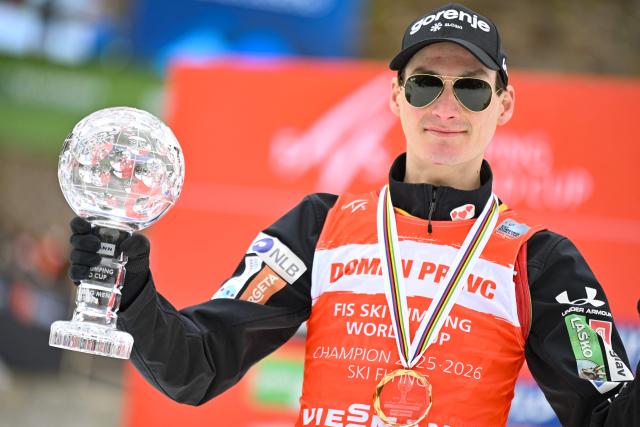 Slovenia's Domen Prevc celebrates his first place in the Ski Flying classification with the crystal globe on the podium after the Men's Individual Large Hill event at the FIS Jumping World Cup in Planica on March 29, 2026. (Photo by JURE MAKOVEC / AFP)