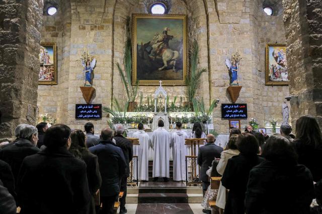 Faithful attend the Palm Sunday service at the Maronite Church of Saint George in the southern Lebanese border Christian village of Qlayaa on March 29, 2026. Qlayaa's local parish priest, Father Pierre Rai, was died on March 9 of wounds sustained from Israeli tank fire, sparking anger and fear. Lebanon was drawn into the Middle East war last week when Iran-backed militant group Hezbollah attacked Israel in response to the killing of the Iranian supreme leader during US-Israeli strikes on February 28. (Photo by AFP)
