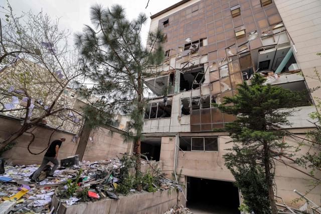 A man searches the debris outside an office building that housed the offices of the Doha-headquartered news network Al Araby TV following a missile strike earlier in the day in Tehran on March 29, 2026. The network on March 29 criticised a strike on the building hosting its Tehran office, as Israel and the US pressed an aerial campaign against Iran. It added that, according to the Iranian Red Crescent 10 people, had been injured in the Sunday morning strike. (Photo by ATTA KENARE / AFP) / 