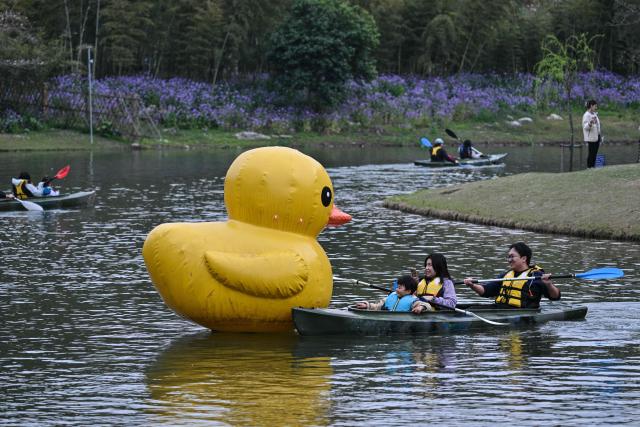 People enjoy kayaking at the Century Park in Shanghai on March 29, 2026. (Photo by Hector RETAMAL / AFP)