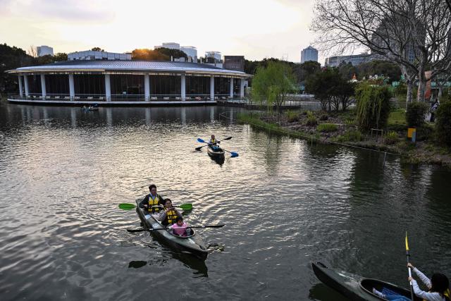 People enjoy kayaking at Century Park in Shanghai on March 29, 2026. (Photo by Hector RETAMAL / AFP)