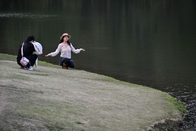 A woman poses for pictures at the Century Park in Shanghai on March 29, 2026. (Photo by Hector RETAMAL / AFP)