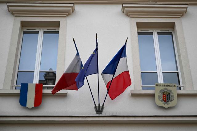 This photograph shows the French and European flags and the city emblem (R) above the entrance of the city hall in Aubervilliers on March 29, 2026. (Photo by Blanca CRUZ / AFP)