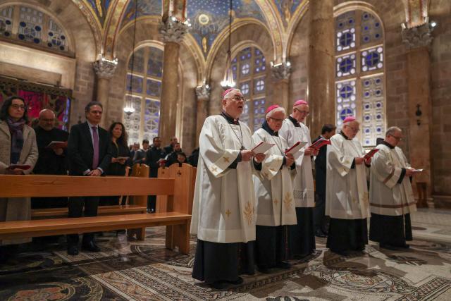 Members of the clergy and faithfuls attend a prayer service in the Church of All Nations held by Latin Patriarch of Jerusalem, Cardinal Pierbattista Pizzaballa, to mark Palm Sunday in Jerusalem on March 29, 2026, following the cancellation of the traditional Palm Sunday procession from the Mount of Olives amid restrictions on gathering in large groups and the US-Israeli war on Iran. Israeli authorities have cancelled the Palm Sunday procession in Jerusalem due to wartime restrictions. Israel has been at war since it and the US launched strikes against Iran on February 28, sparking swift retaliation by the Islamic republic which responded with missile attacks across the region. (Photo by Ammar Awad / POOL / AFP)