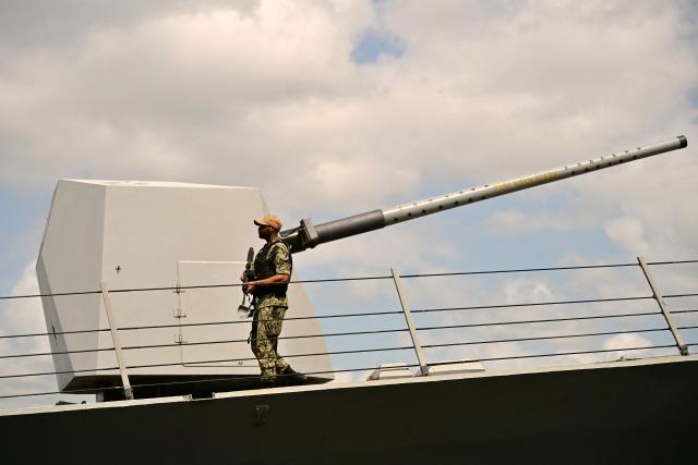 A soldier stands guard on the deck of the US Navy Arleigh Burke-class guided-missile destroyer USS Gridley (DDG 101), docked at the Amador cruise terminal in Panama City on March 29, 2026. The ship reached the country alongside the aircraft carrier USS Nimitz as part of the multinational maritime cooperation exercises “Mares del Sur 2026.” (Photo by MARTIN BERNETTI / AFP)