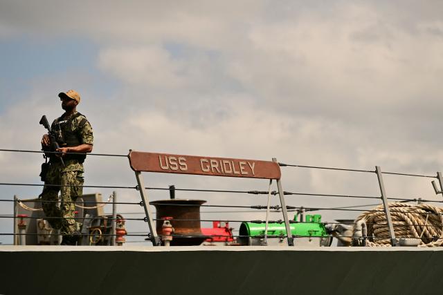 A soldier stands guard on the deck of the US Navy Arleigh Burke-class guided-missile destroyer USS Gridley (DDG 101), docked at the Amador cruise terminal in Panama City on March 29, 2026. The ship reached the country alongside the aircraft carrier USS Nimitz as part of the multinational maritime cooperation exercises “Mares del Sur 2026.” (Photo by MARTIN BERNETTI / AFP)