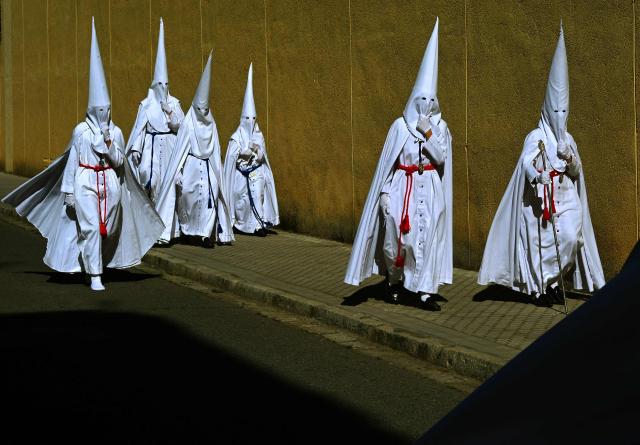 Penitents from the La Paz brotherhood make their way to the church to participate in the Palm Sunday procession in Seville on March 29, 2026. Spain's colourful Holy Week celebrations begin today, featuring centuries-old processions of the faithful carrying flower-covered floats topped with statues of Christ or the Virgin Mary that draw huge crowds. Organised by various religious brotherhoods, or "confradias", the parades are held across the country in the week leading up to Easter Sunday, which this year in the Roman Catholic Church falls on April 5. (Photo by CRISTINA QUICLER / AFP)