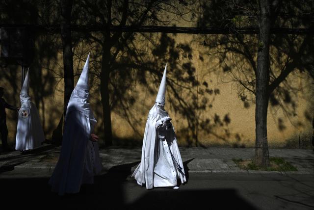 Penitents from the La Paz brotherhood make their way to the church to participate in the Palm Sunday procession in Seville on March 29, 2026. Spain's colourful Holy Week celebrations begin today, featuring centuries-old processions of the faithful carrying flower-covered floats topped with statues of Christ or the Virgin Mary that draw huge crowds. Organised by various religious brotherhoods, or "confradias", the parades are held across the country in the week leading up to Easter Sunday, which this year in the Roman Catholic Church falls on April 5. (Photo by Cristina Quicler / AFP)