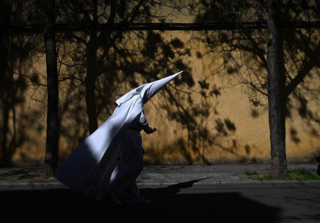 TOPSHOT - A penitent from the La Paz brotherhood goes to the church to participate in the Palm Sunday procession in Seville on March 29, 2026. Spain's colourful Holy Week celebrations begin today, featuring centuries-old processions of the faithful carrying flower-covered floats topped with statues of Christ or the Virgin Mary that draw huge crowds. Organised by various religious brotherhoods, or "confradias", the parades are held across the country in the week leading up to Easter Sunday, which this year in the Roman Catholic Church falls on April 5. (Photo by CRISTINA QUICLER / AFP)