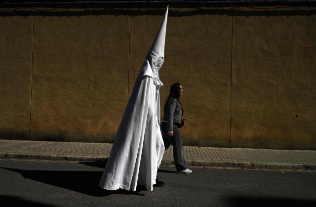 TOPSHOT - A penitent from the La Paz brotherhood goes to the church to participate in the Palm Sunday procession in Seville on March 29, 2026. Spain's colourful Holy Week celebrations begin today, featuring centuries-old processions of the faithful carrying flower-covered floats topped with statues of Christ or the Virgin Mary that draw huge crowds. Organised by various religious brotherhoods, or "confradias", the parades are held across the country in the week leading up to Easter Sunday, which this year in the Roman Catholic Church falls on April 5. (Photo by CRISTINA QUICLER / AFP)