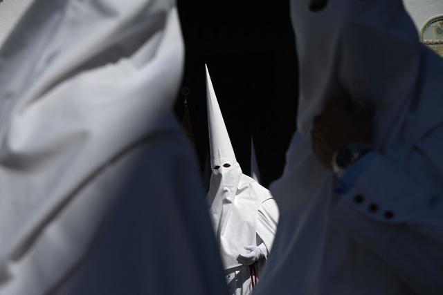 Penitents from the La Paz brotherhood make their way to the church to participate in the Palm Sunday procession in Seville on March 29, 2026. Spain's colourful Holy Week celebrations begin today, featuring centuries-old processions of the faithful carrying flower-covered floats topped with statues of Christ or the Virgin Mary that draw huge crowds. Organised by various religious brotherhoods, or "confradias", the parades are held across the country in the week leading up to Easter Sunday, which this year in the Roman Catholic Church falls on April 5. (Photo by CRISTINA QUICLER / AFP)