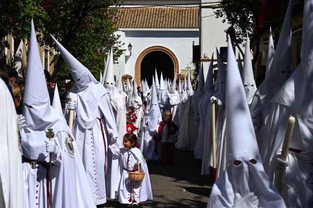 Penitents from the La Paz brotherhood parade in the Palm Sunday procession in Seville on March 29, 2026. Spain's colourful Holy Week celebrations begin today, featuring centuries-old processions of the faithful carrying flower-covered floats topped with statues of Christ or the Virgin Mary that draw huge crowds. Organised by various religious brotherhoods, or "confradias", the parades are held across the country in the week leading up to Easter Sunday, which this year in the Roman Catholic Church falls on April 5. (Photo by CRISTINA QUICLER / AFP)