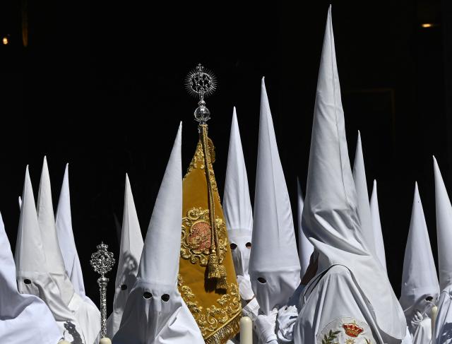 Penitents from the La Paz brotherhood parade in the Palm Sunday procession in Seville on March 29, 2026. Spain's colourful Holy Week celebrations begin today, featuring centuries-old processions of the faithful carrying flower-covered floats topped with statues of Christ or the Virgin Mary that draw huge crowds. Organised by various religious brotherhoods, or "confradias", the parades are held across the country in the week leading up to Easter Sunday, which this year in the Roman Catholic Church falls on April 5. (Photo by CRISTINA QUICLER / AFP)