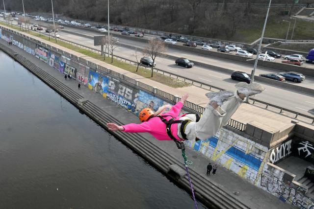 A woman bungee jumps from a 26-meter-high pedestrian bridge over the Dnipro River in Kyiv on March 29, 2026. (Photo by Sergei SUPINSKY / AFP)