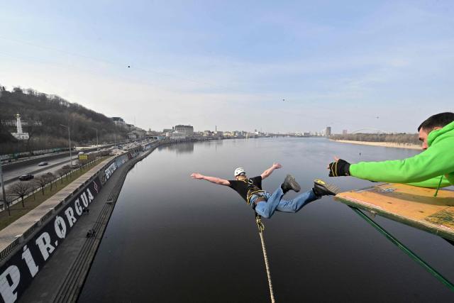A man bungee jumps from a 26-meter-high pedestrian bridge over the Dnipro River in Kyiv on March 29, 2026. (Photo by Sergei SUPINSKY / AFP)