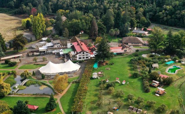 (FILES) This aerial view shows Villa Baviera Village, formerly known as Colonia Dignidad (Dignity Colony), now called Villa Baviera, near Parral, Maule Province, Chile on April 15, 2025. Chile's new right-wing government will reverse plans to expropriate Colonia Dignidad, a German-themed settlement that served as a torture center when Augusto Pinochet was in power, a government minister said on March 29, 2026. The place featured a swimming pool, manicured lawns, and lush forest backdrop, making it look like a nice holiday getaway spot. (Photo by RODRIGO ARANGUA / AFP)