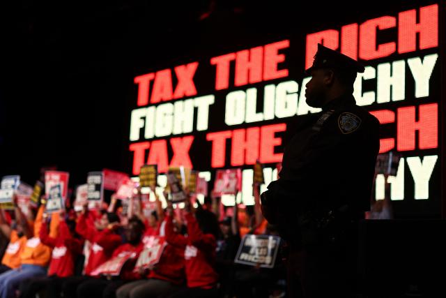 A police officer is seen as US Senator Bernie Sanders, Independent from Vermont, (out of frame) speaks during a "Tax the Rich" rally at Lehman College in the Bronx borough of New York City on March 29, 2026. (Photo by CHARLY TRIBALLEAU / AFP)