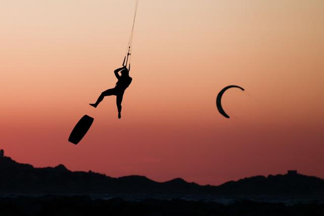 A kitesurfer soars into the air above sea as the sun sets in Marseille, south-eastern France on March 29, 2026. (Photo by Thibaud MORITZ / AFP)