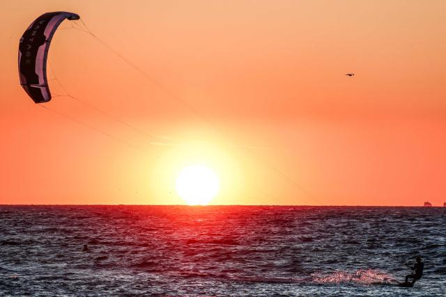 A kitesurfer surfs as the sun sets in Marseille, south-eastern France on March 29, 2026. (Photo by Thibaud MORITZ / AFP)