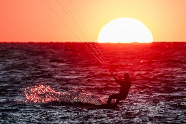 A kitesurfer surfs as the sun sets in Marseille, south-eastern France on March 29, 2026. (Photo by Thibaud MORITZ / AFP)